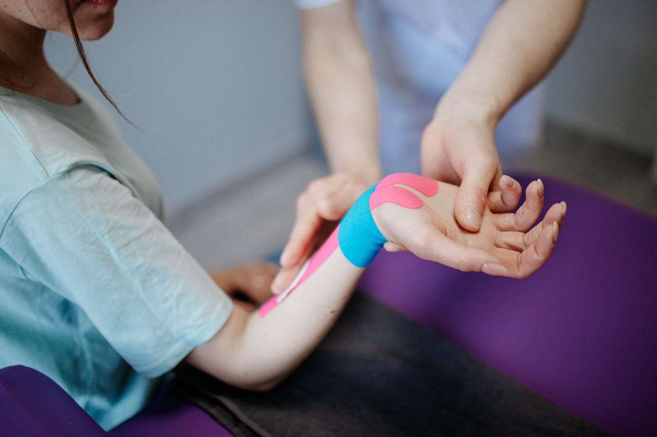 Close-up of a therapist applying kinesio tape for pain relief during a therapy session.